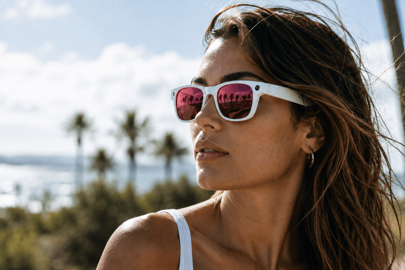 A traveler wearing Cyan World Traveler smart glasses, palm trees and coastline reflected in the lenses